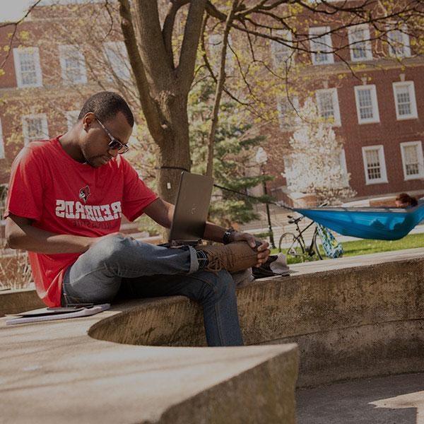 一个学生坐在院子里的混凝土长凳上.