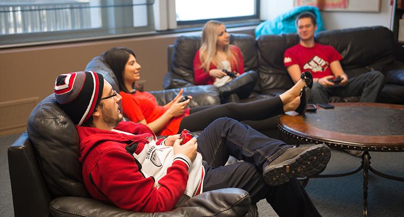 International students relaxing on a couch, playing video games.